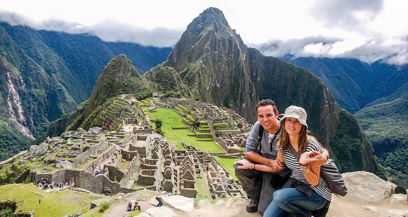 Pareja sonriendo frente a Machu Picchu